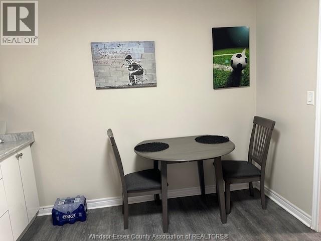A dining room with a table and chairs and two pictures on the wall.