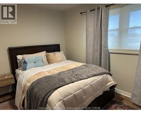 A bedroom with a large bed and a window with curtains.