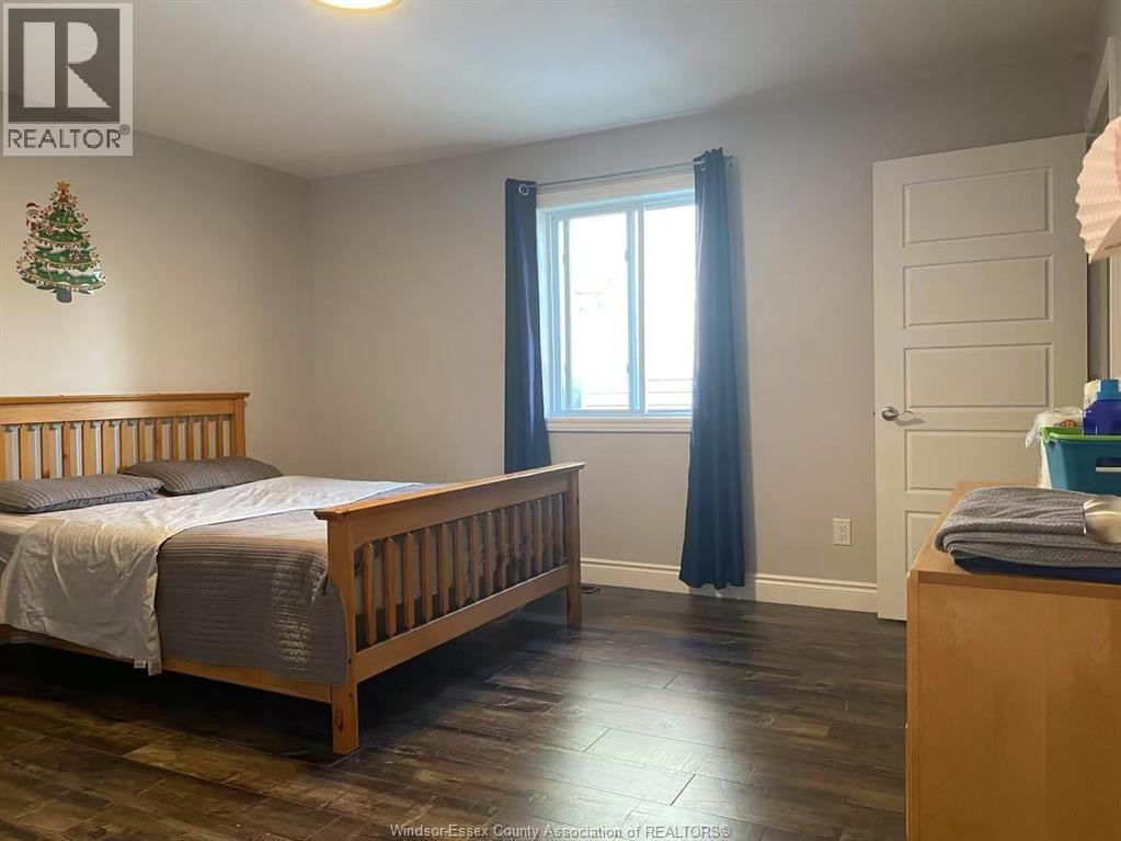 A bedroom with a bed, a window with blue curtains, and a wooden dresser.