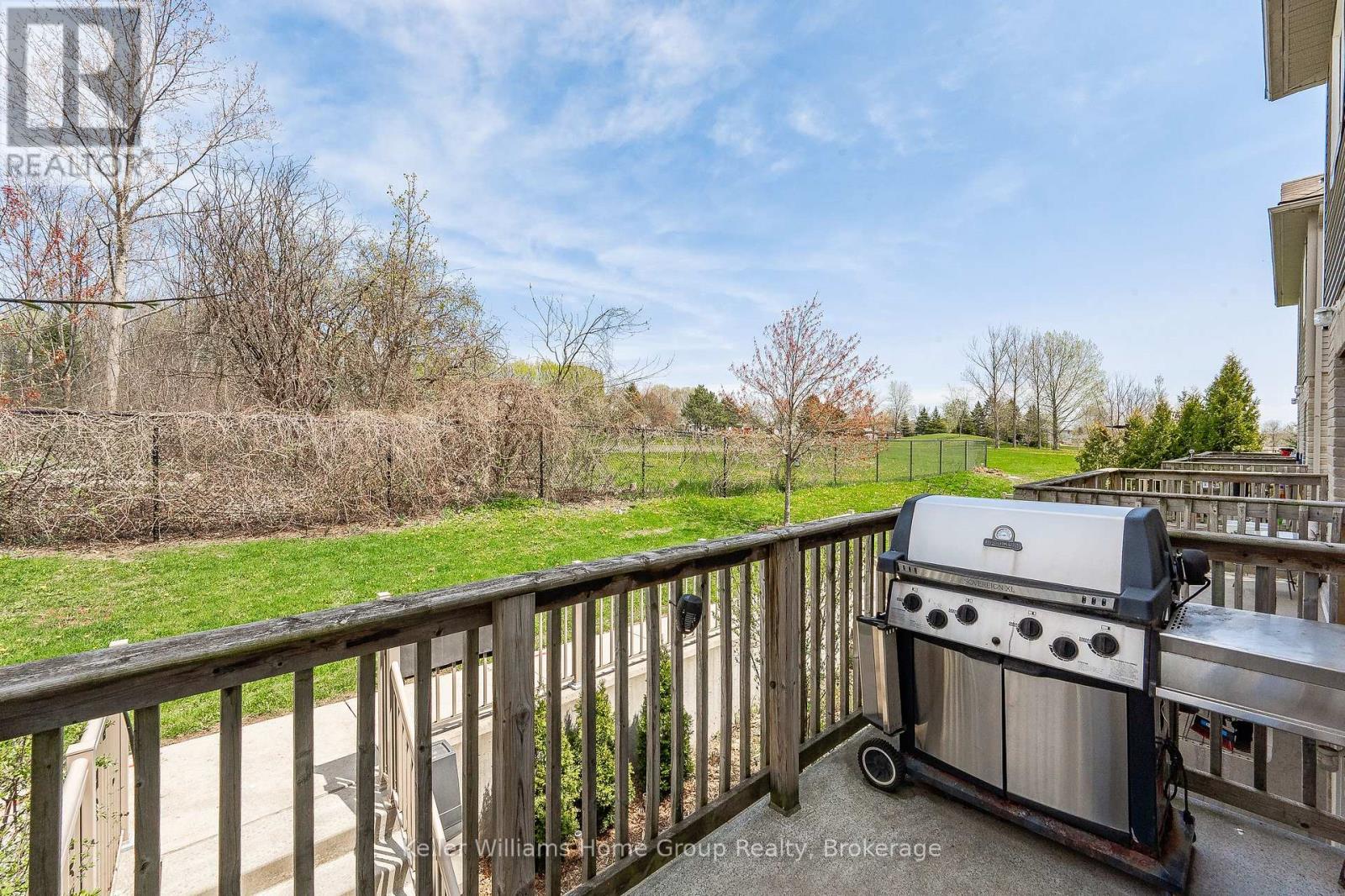 A BBQ grill is on a deck with a view of a grassy area.