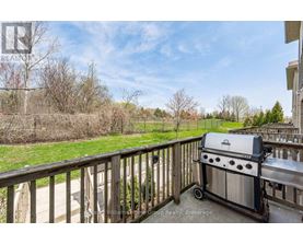 A BBQ grill is on a deck with a view of a grassy area.