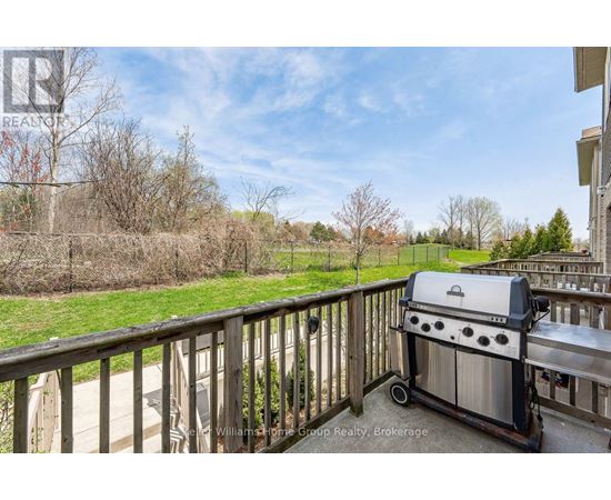 A BBQ grill is on a deck with a view of a grassy area.