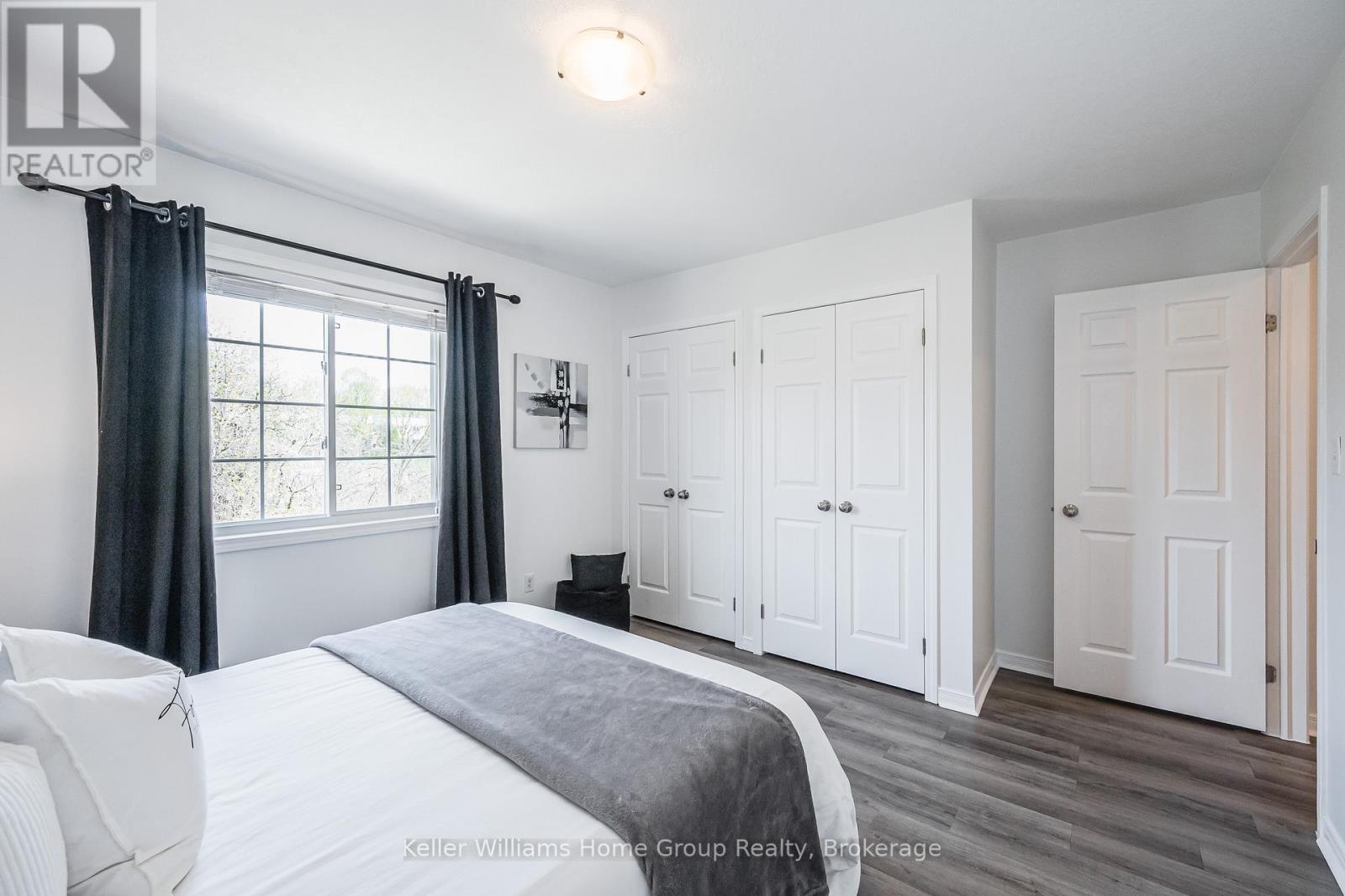 A bedroom with a large bed and a window with curtains.