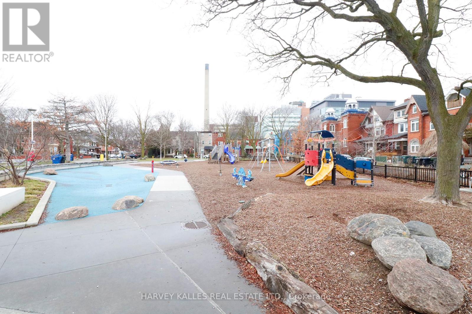 A playground with a slide, swimming pool and a tree.