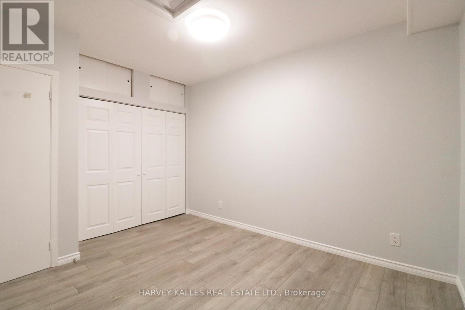 A white bedroom with a door and a light on the ceiling.