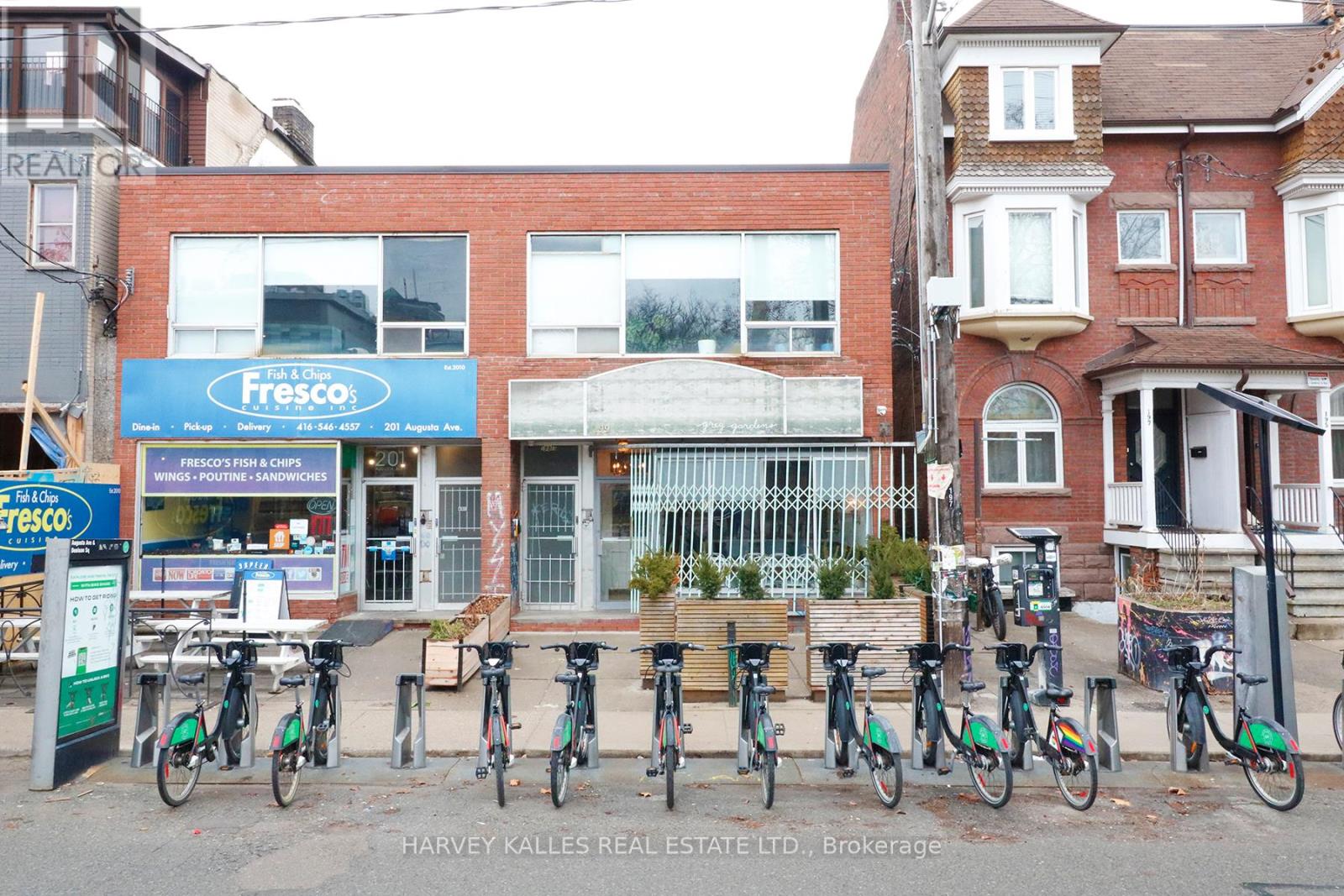 A row of bicycles are parked in front of a building with a blue sign that says Fresco.