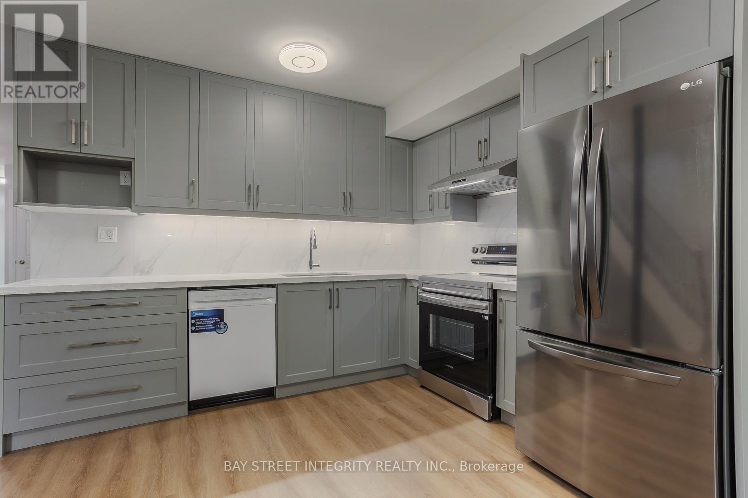 A modern kitchen with stainless steel appliances and grey cabinets.