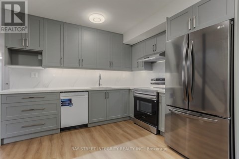 A modern kitchen with stainless steel appliances and grey cabinets.