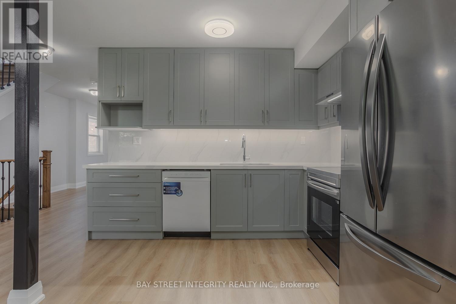 A modern kitchen with stainless steel appliances and grey cabinets.