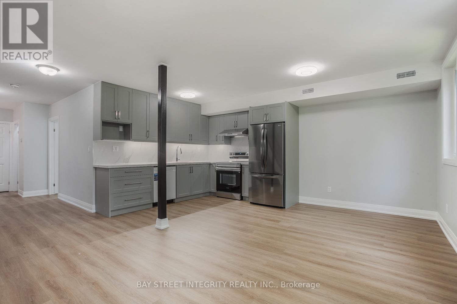 A spacious kitchen with wooden floors and grey cabinets.
