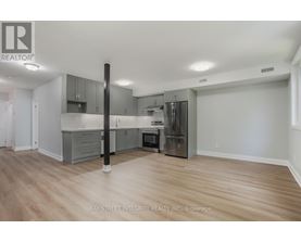 A spacious kitchen with wooden floors and grey cabinets.