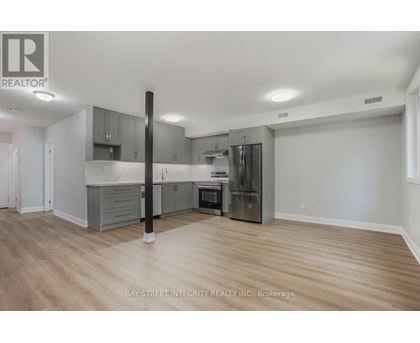 A spacious kitchen with wooden floors and grey cabinets.