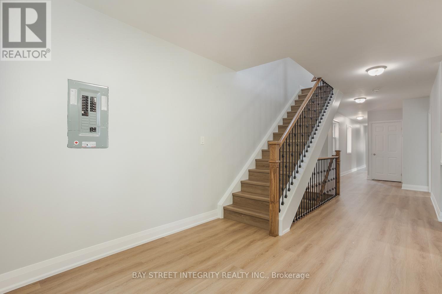 A spacious hallway with a staircase and a wall-mounted elevator control panel.