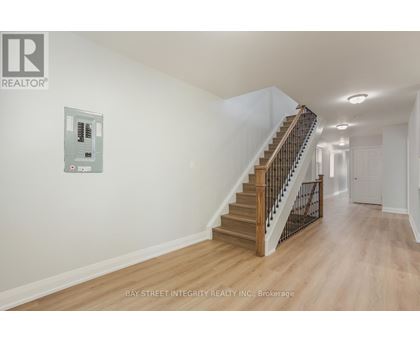 A spacious hallway with a staircase and a wall-mounted elevator control panel.