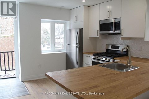 A kitchen with a wooden counter top and stainless steel appliances.