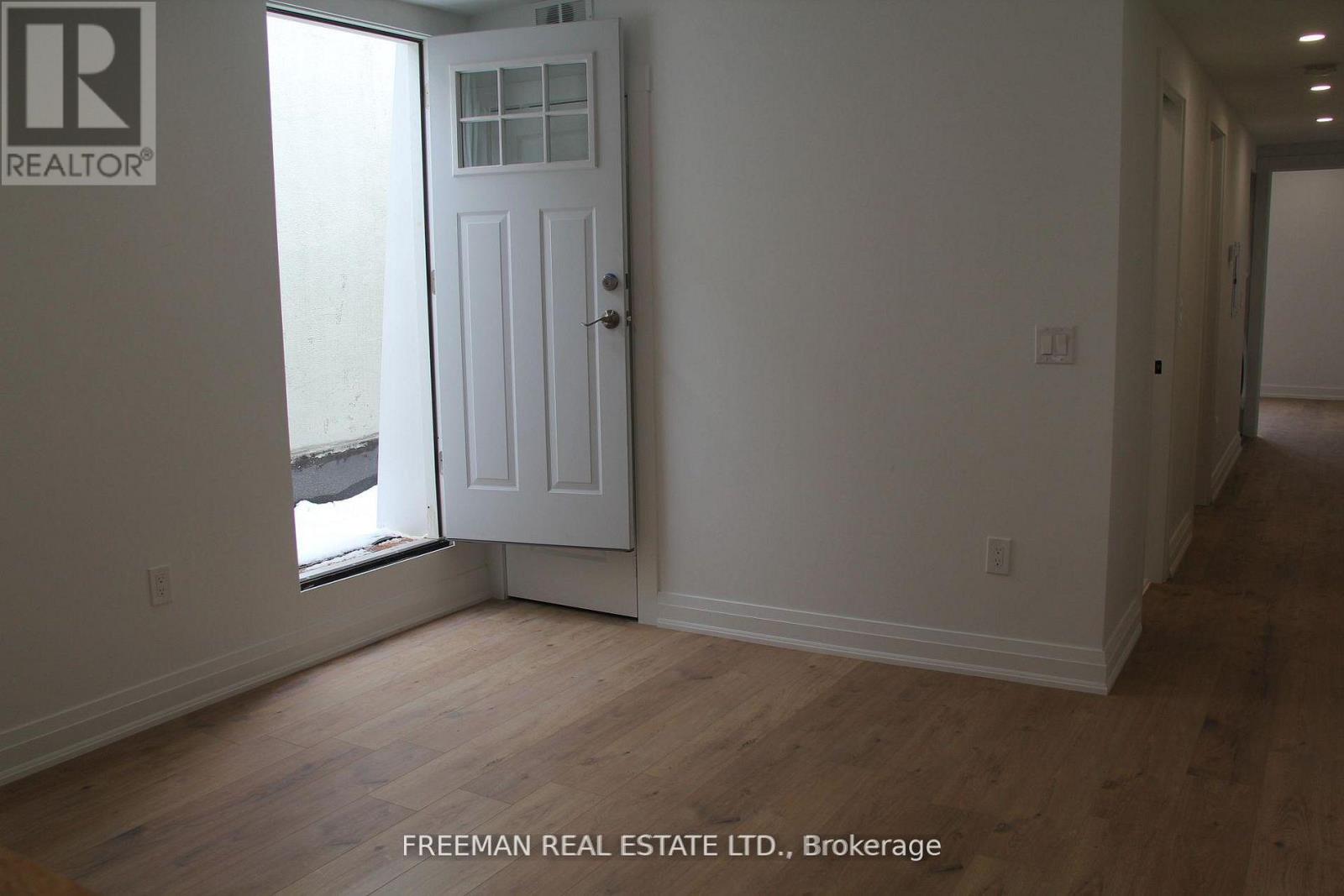 A white door is in a room with wood floors and white walls.