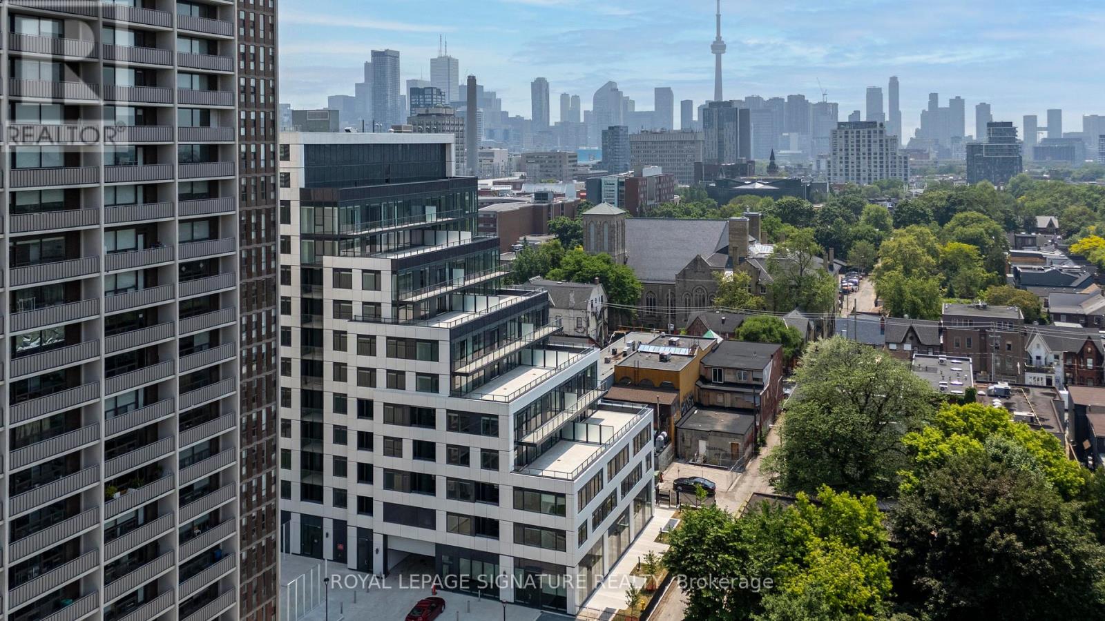 A cityscape with a mix of modern and older buildings, with the CN Tower visible in the distance.