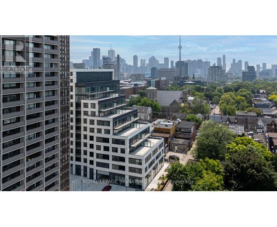 A cityscape with a mix of modern and older buildings, with the CN Tower visible in the distance.