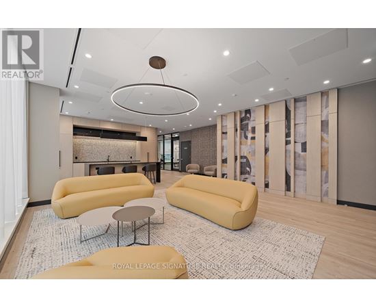 A living room with a yellow sofa and a circular light fixture on the ceiling.