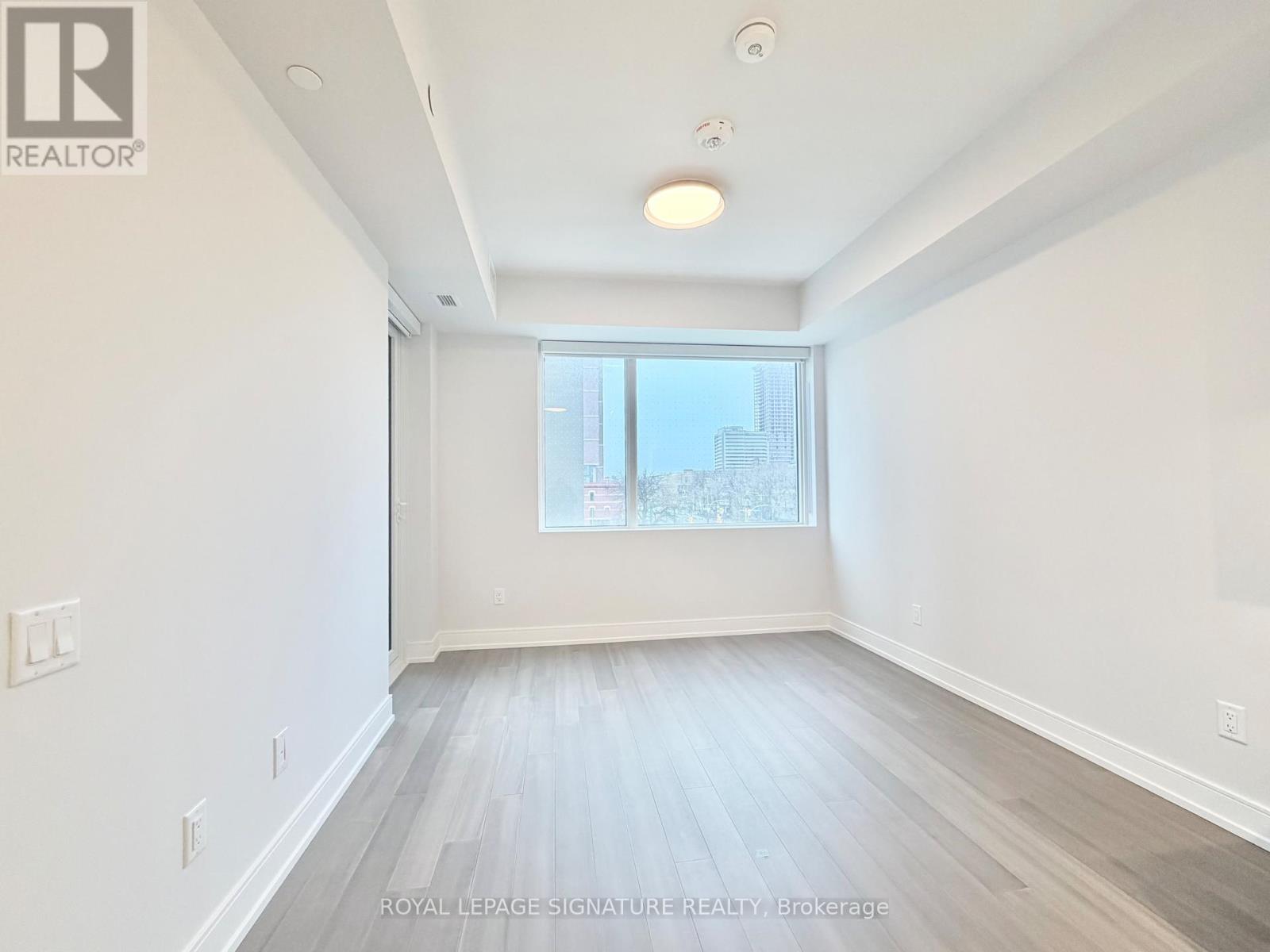 A spacious room with a window and wooden flooring.