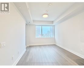 A spacious room with a window and wooden flooring.