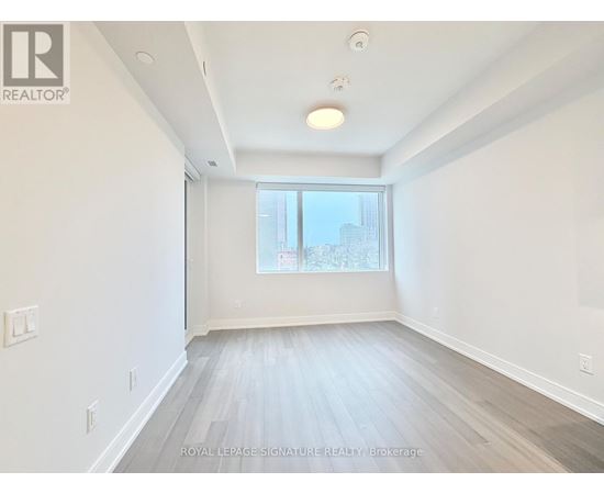 A spacious room with a window and wooden flooring.