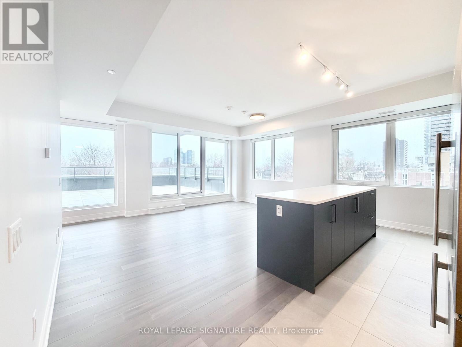 A spacious room with a black cabinet in the middle and a view of the city through the windows.