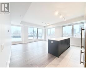 A spacious room with a black cabinet in the middle and a view of the city through the windows.