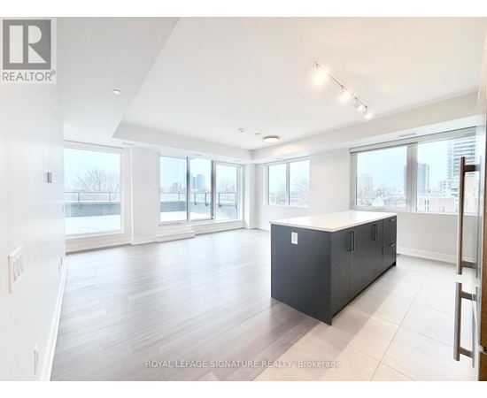 A spacious room with a black cabinet in the middle and a view of the city through the windows.
