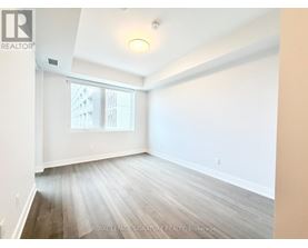 A room with white walls and wooden flooring, with a window showing a building outside.