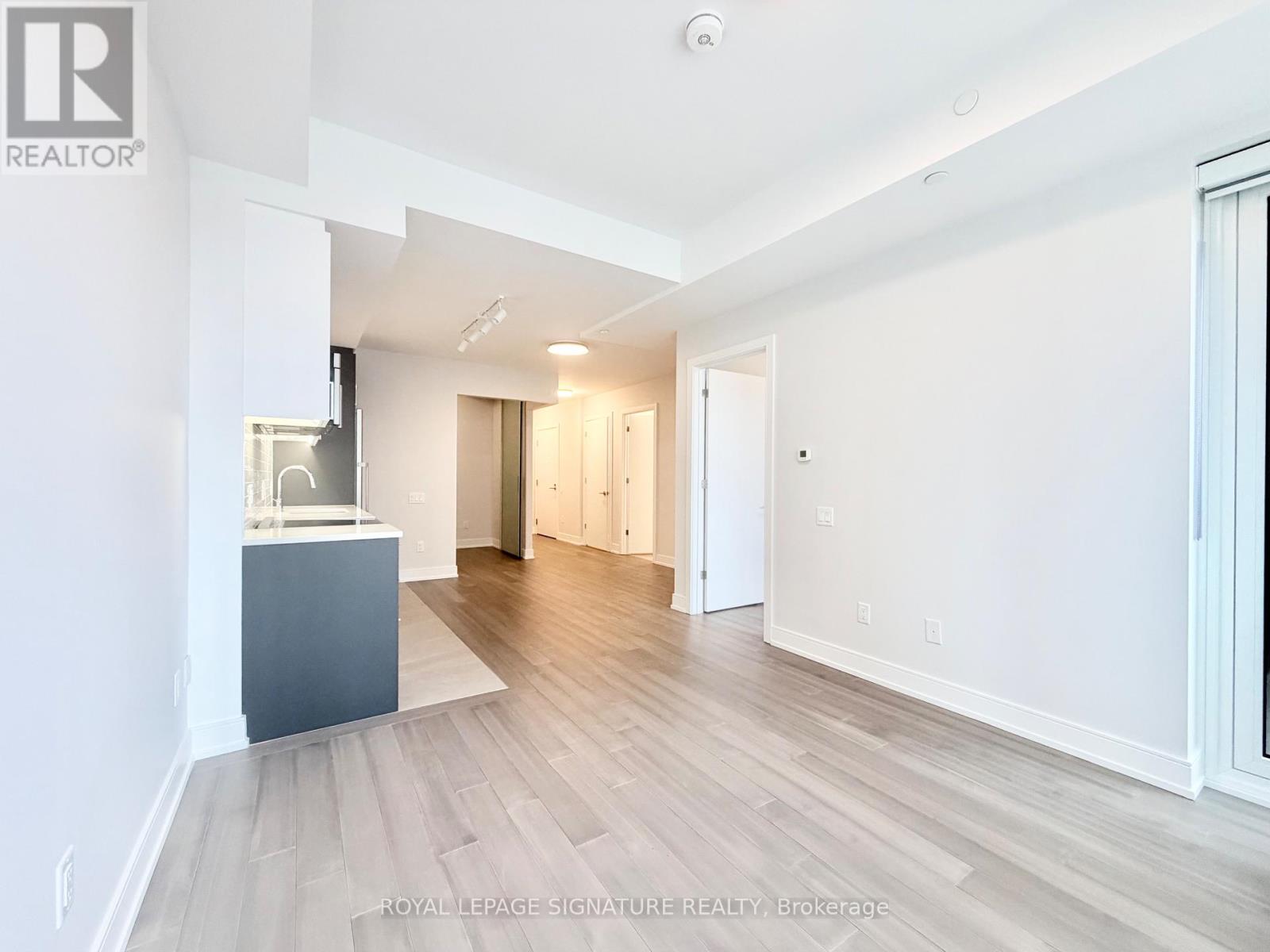 A spacious room with wooden flooring and white walls.