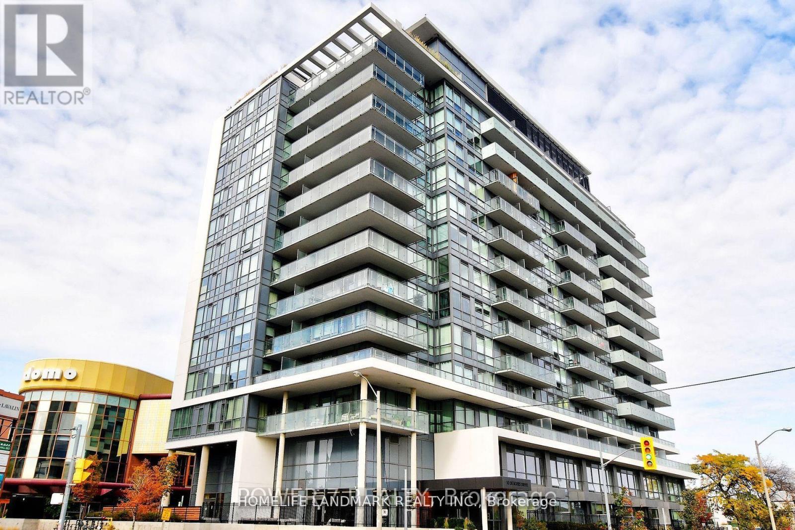 A tall building with many windows and balconies is the main focus of the image.