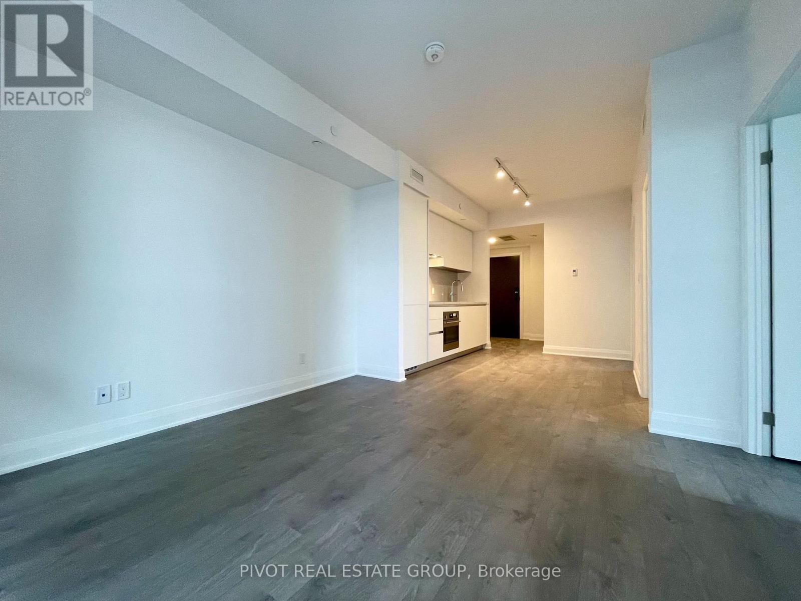 A spacious room with a kitchenette in the background.