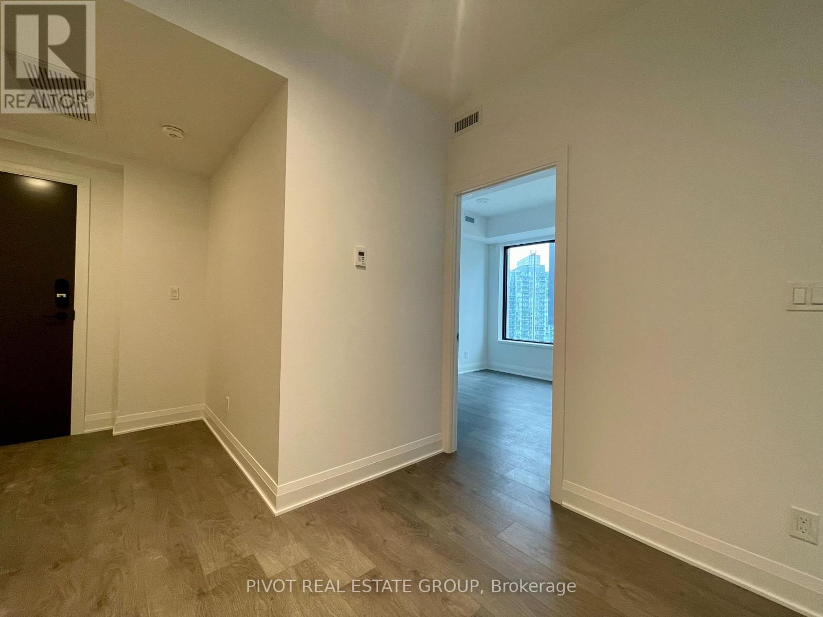A room with a door and a window with a view of a building outside.