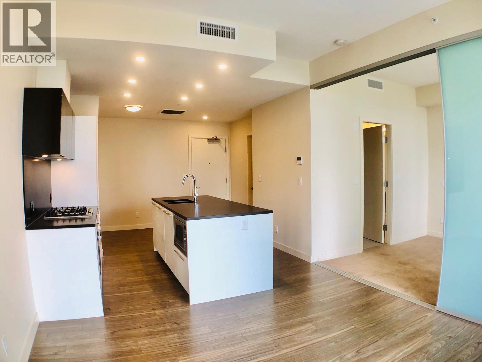 A modern kitchen with a wooden floor and white walls.