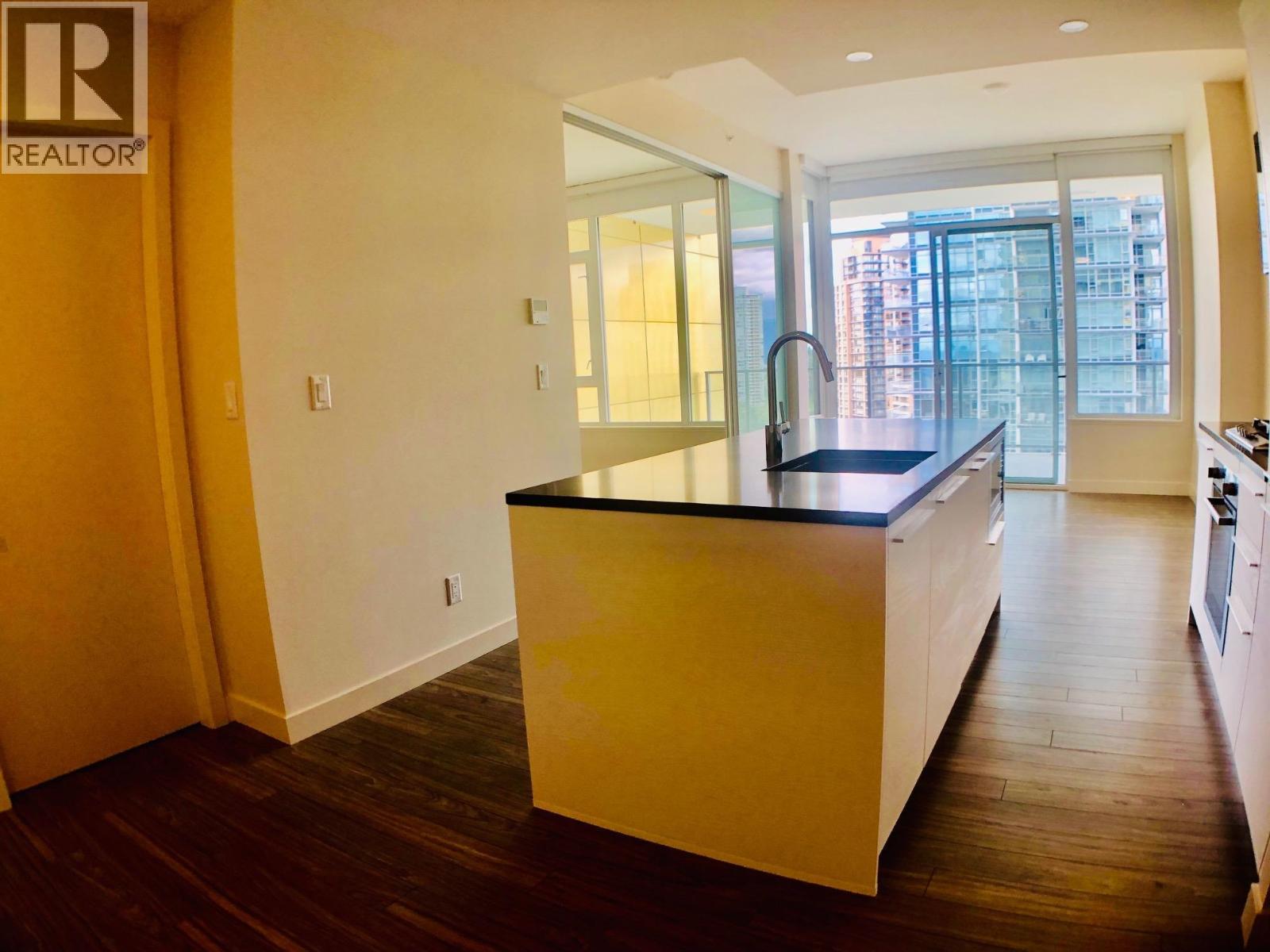 A kitchen with a black countertop and wooden floors.
