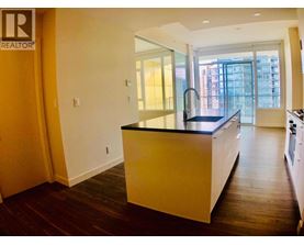 A kitchen with a black countertop and wooden floors.