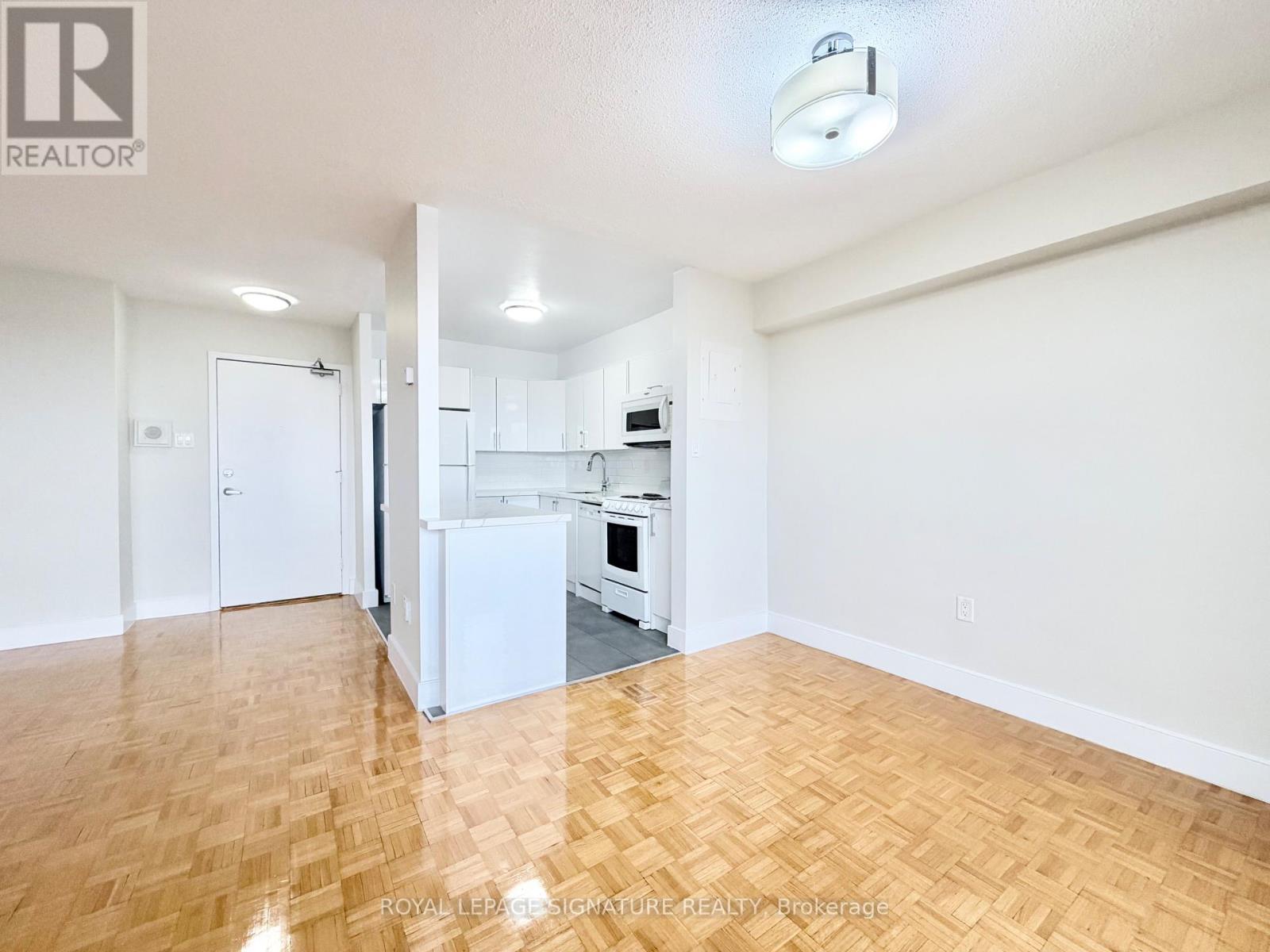 A kitchen with white appliances and wooden floors.