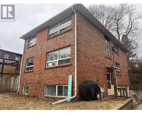 A red brick house with a sign that says "For Sale".