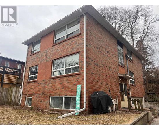 A red brick house with a sign that says "For Sale".