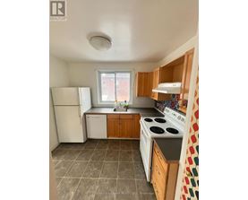 A kitchen with a white refrigerator, white stove, and wooden cabinets.