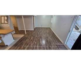 A room with wooden flooring and a RE/MAX sign on the wall.