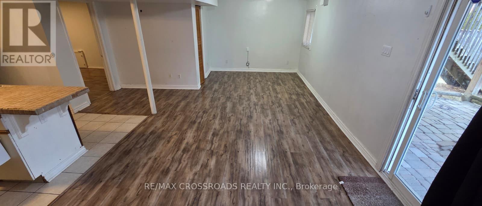 A room with a wooden floor and a door leading outside.