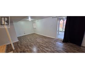 A room with a wooden floor and a door leading outside.