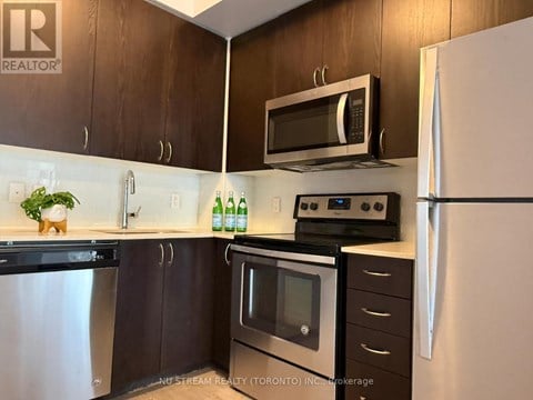A kitchen with a refrigerator, sink, and cabinets.