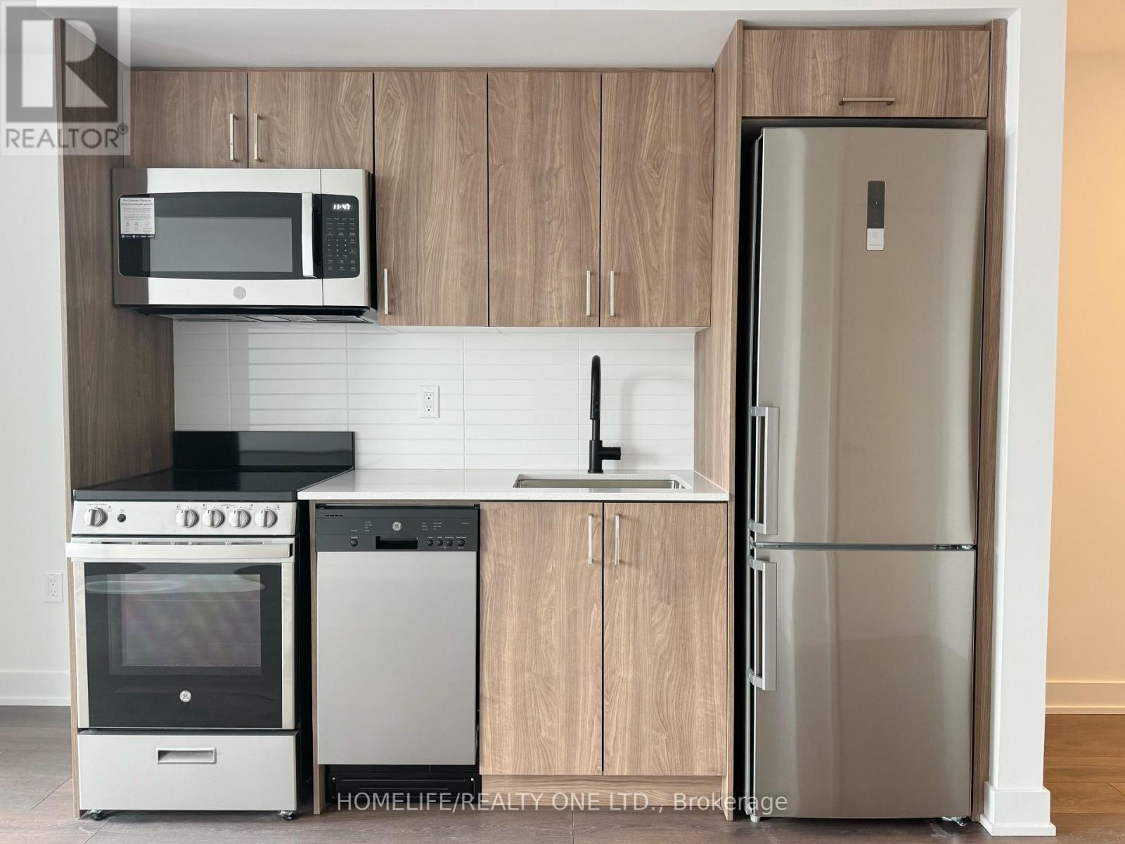 A kitchen with wooden cabinets and a stainless steel refrigerator.