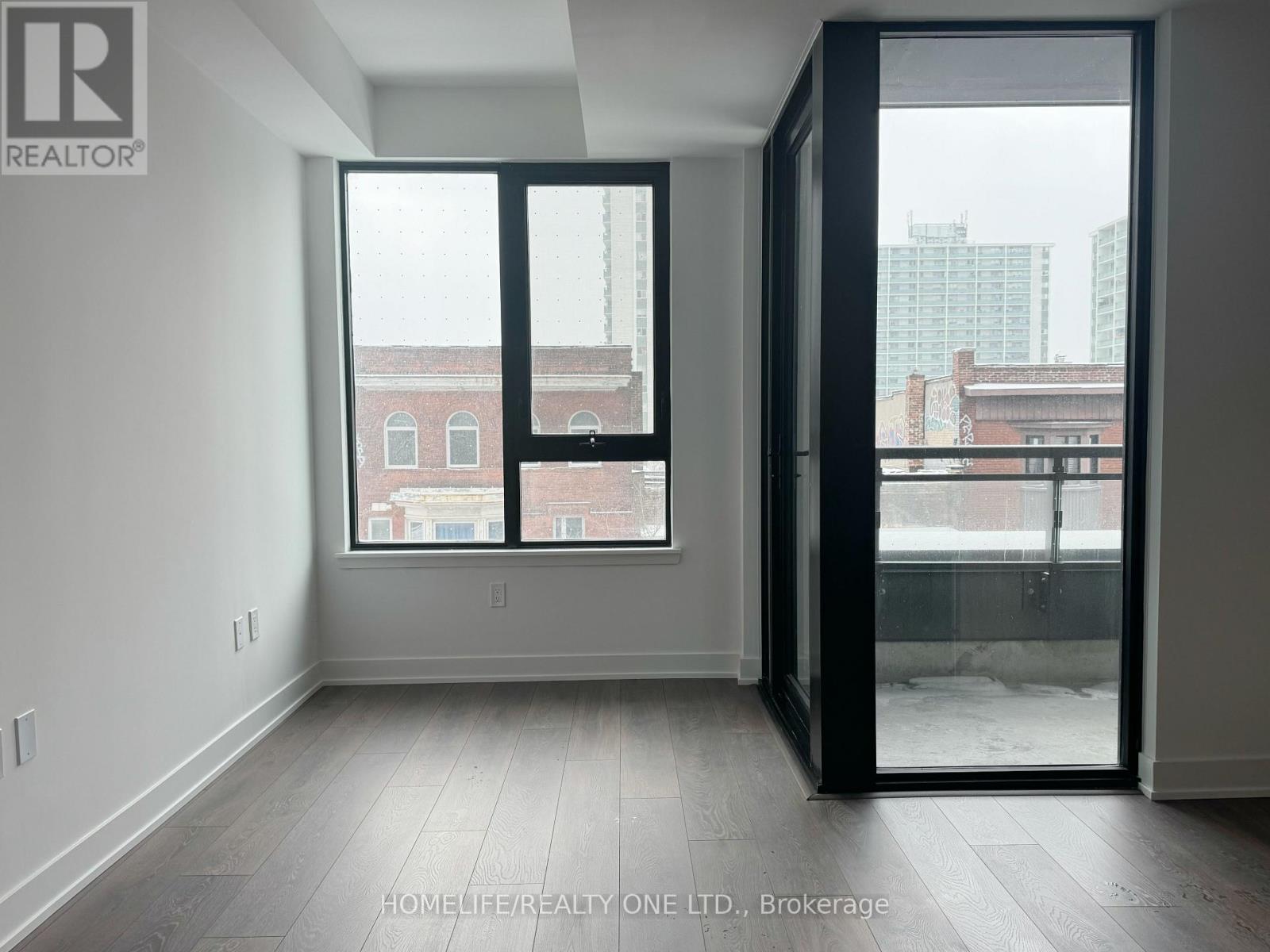 A room with a large window and a sliding glass door leading to a balcony.