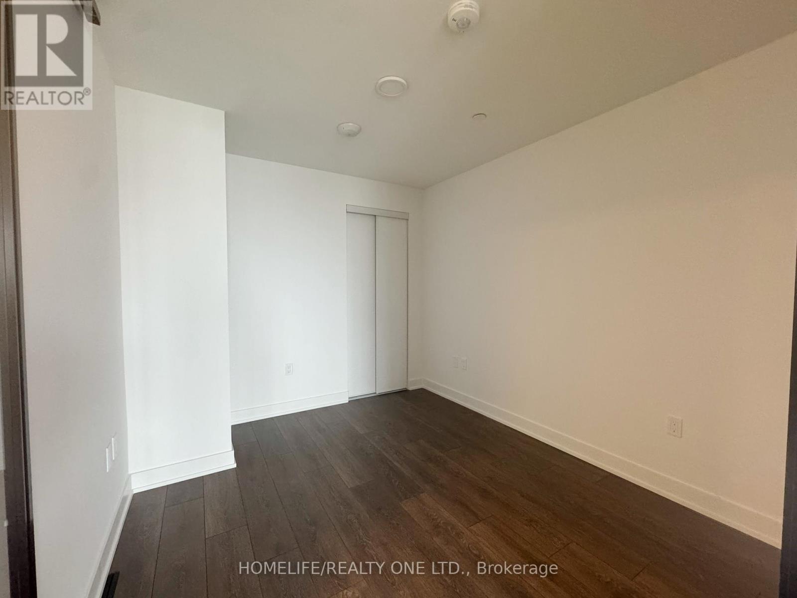 A spacious room with wooden flooring and white walls.