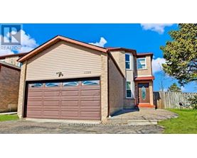 A two-story house with a brown garage door is for sale.