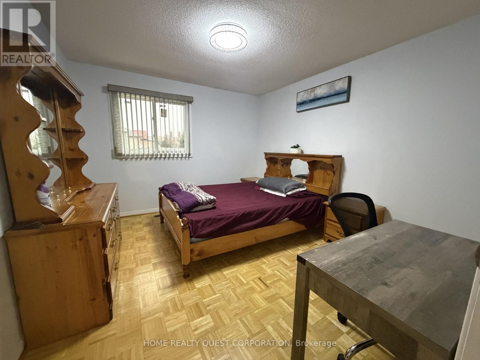 A bedroom with a bed, desk, and chair.